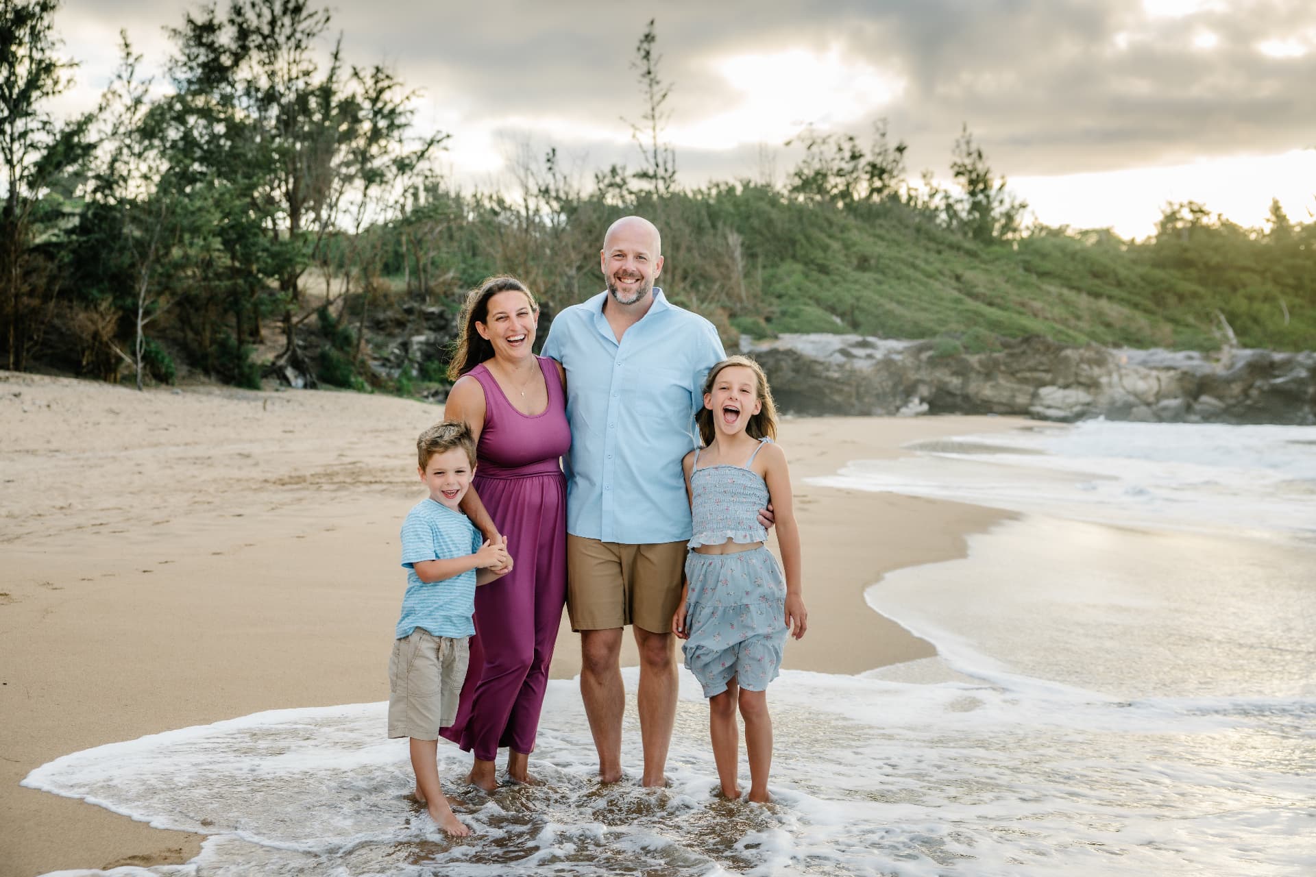 Family laughing together on a Maui beach at sunset