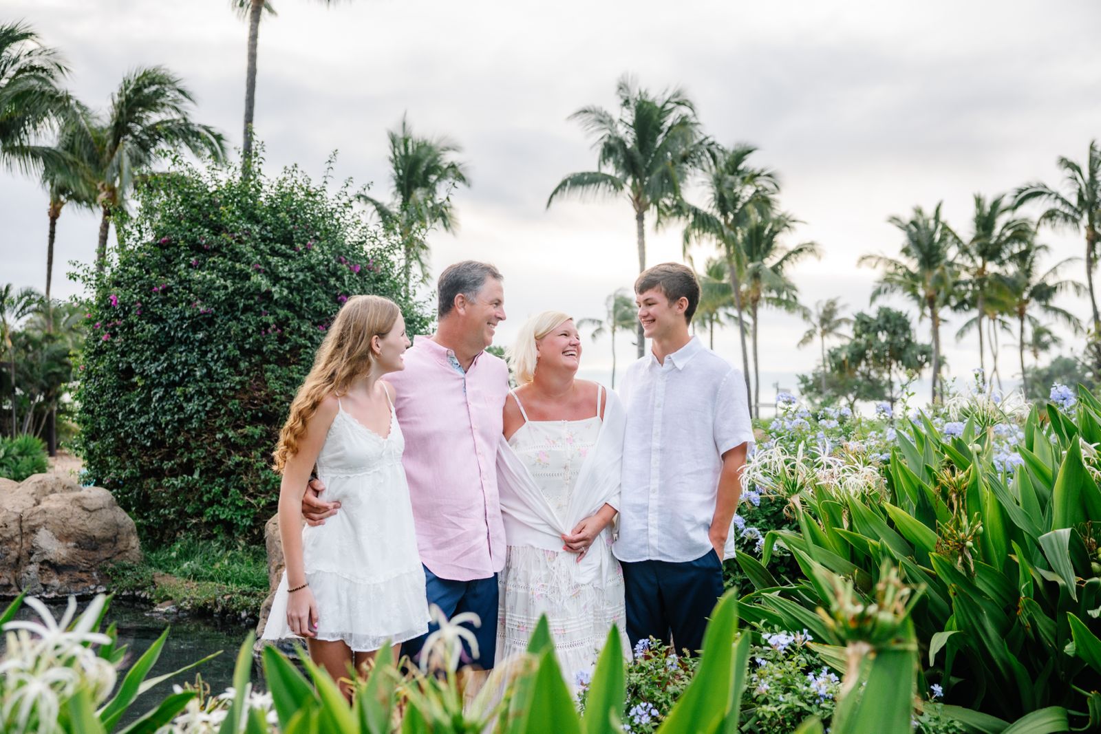 Family of four under palm trees in tropical garden
