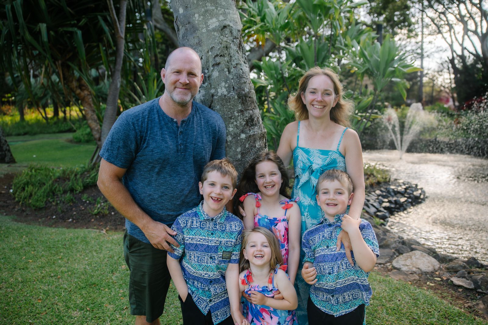 Family with four kids under a tree in tropical garden