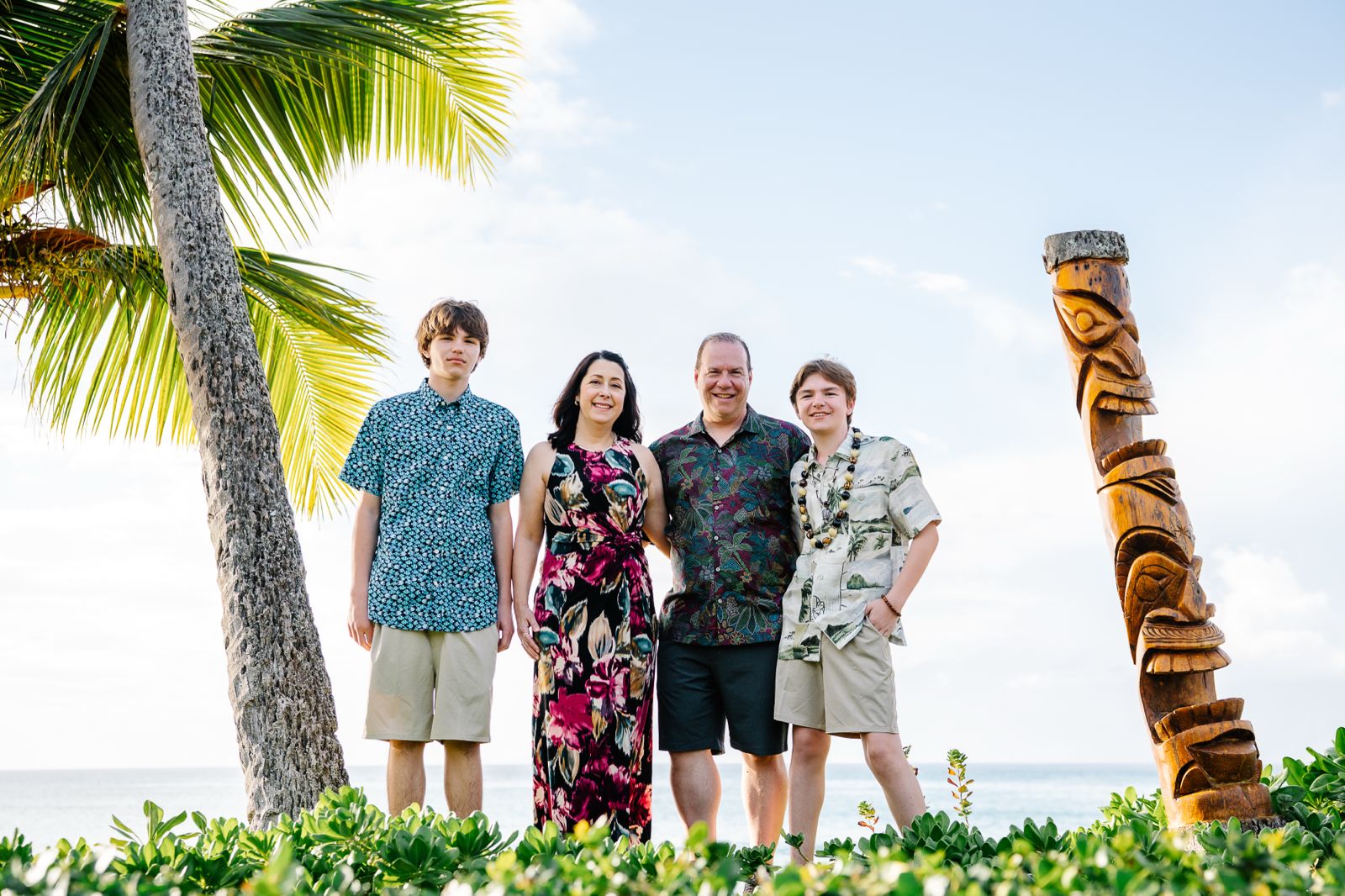 Family of four by palm tree and tiki statue